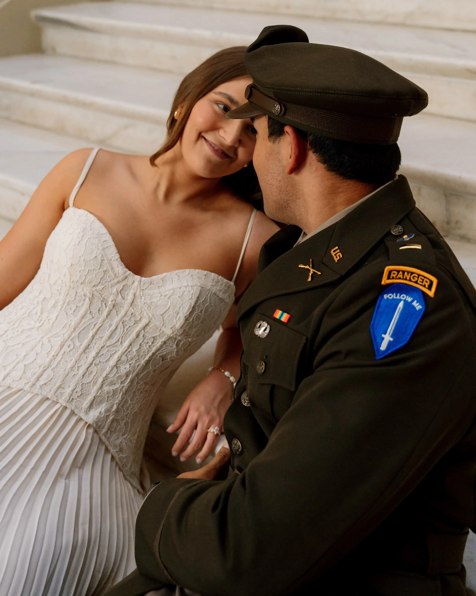 A woman and a man in military uniform sharing an intimate moment on marble steps.