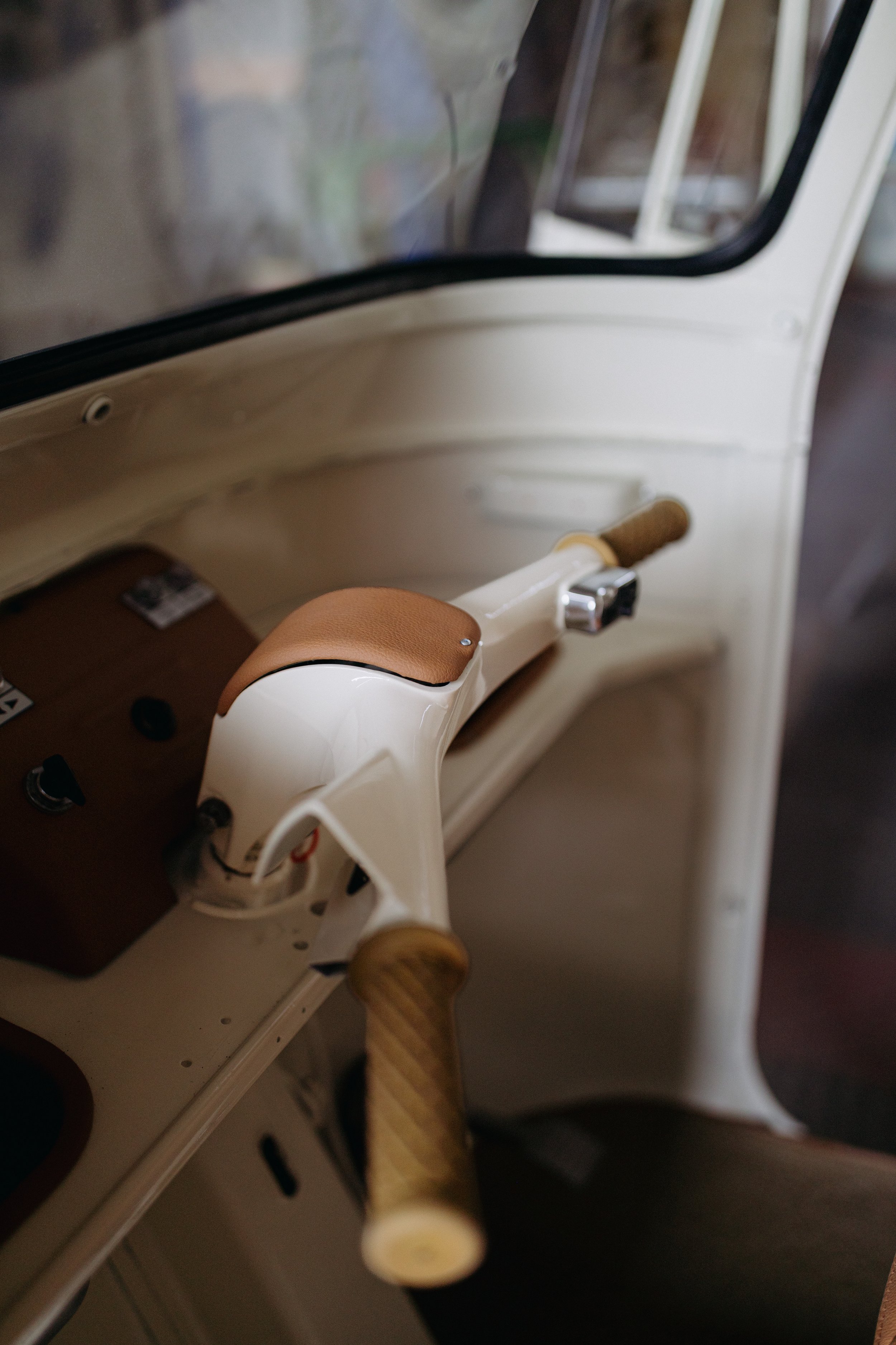 Restored cream handlebar with tan leather trim inside a vintage Piaggio Ape cab