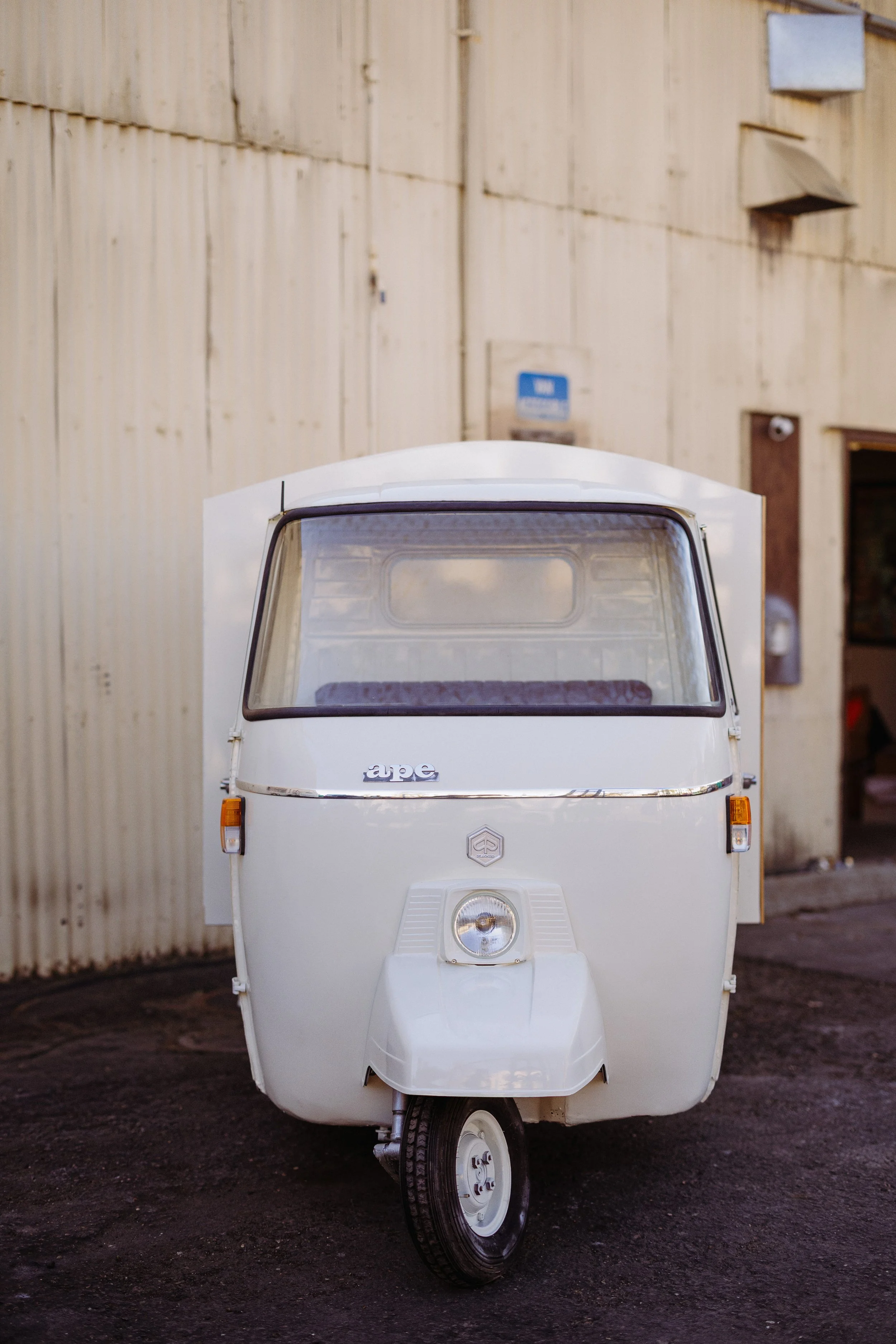 Don Rocco Piaggio Ape mobile bar in front of warehouse