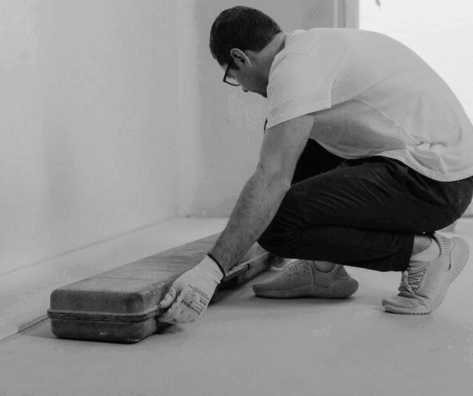 Uomo che sistema una valigia ai piedi di una parete.