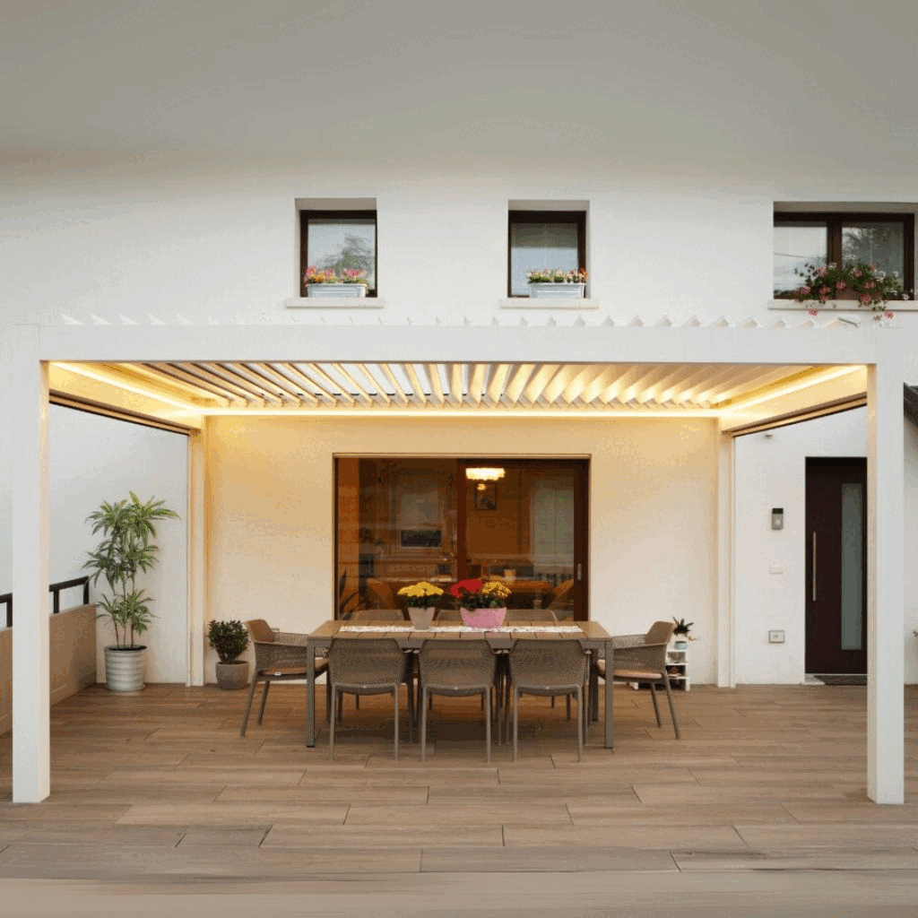 Terrazza con tavolo e sedie, piante e fiori, vista di una casa moderna con tre finestre sul secondo piano.