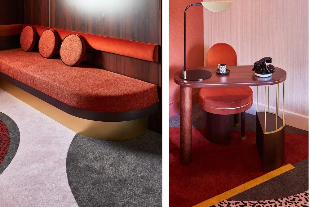 Modern interior design featuring a red sofa with circular cushions, a wooden desk with red chair, a black lamp, and an antique-style telephone.