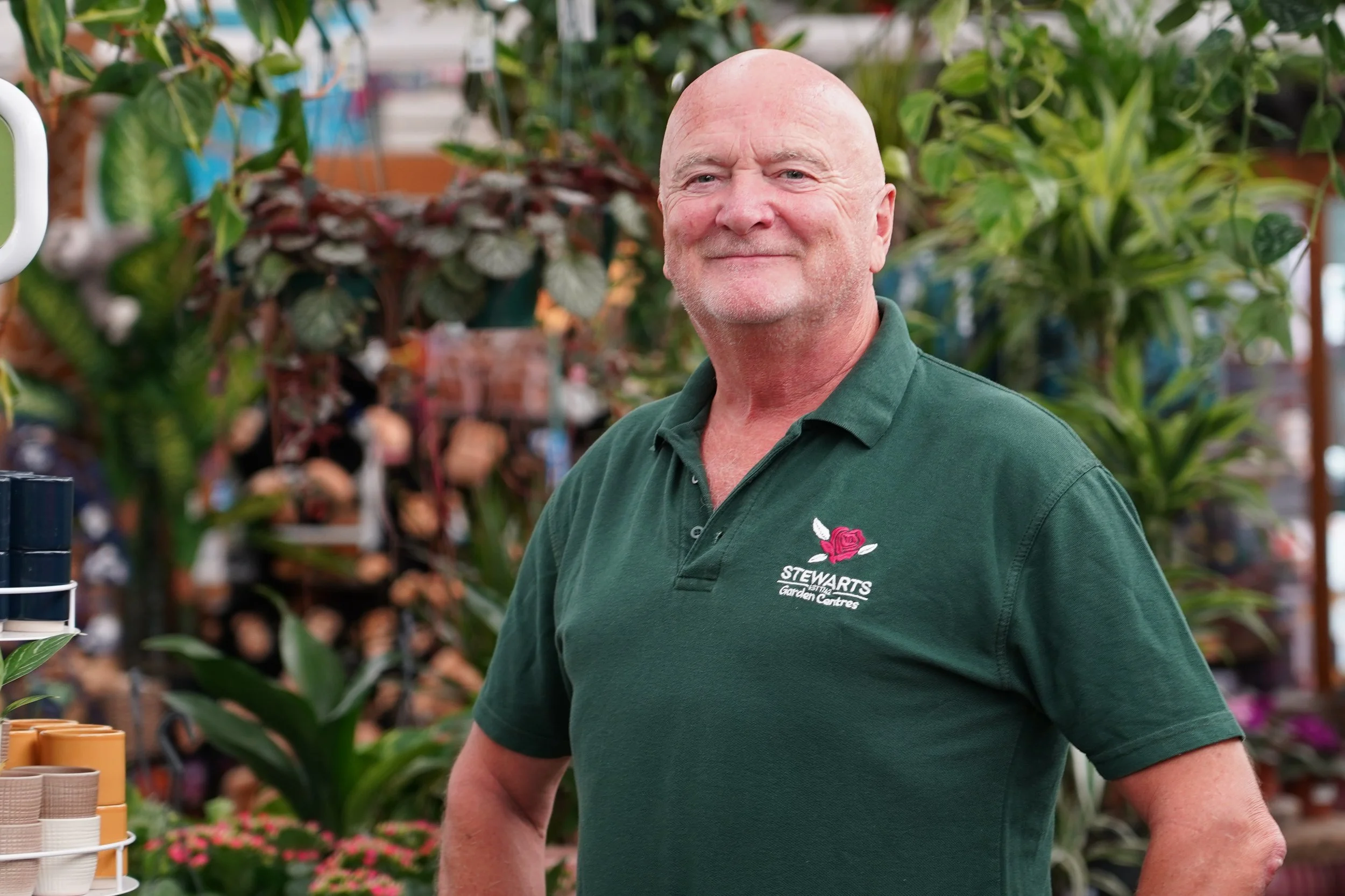 A smiling woman with glasses and gold jewelry, indoors with a blurred background.
