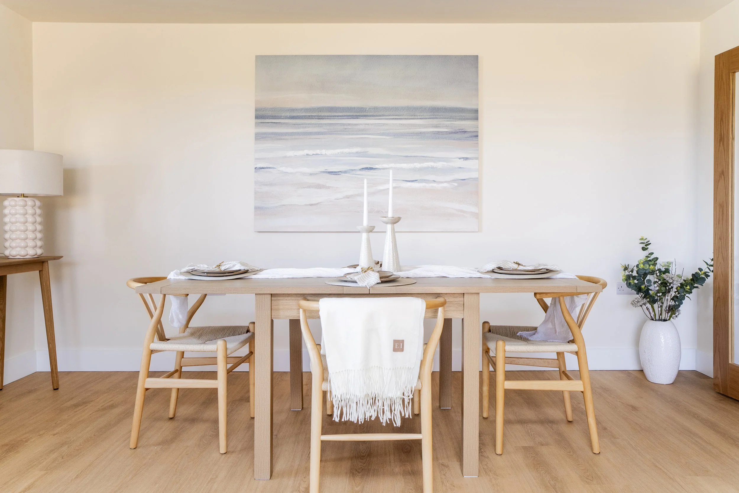 Professionally staged dining room in a Somerset property with a wooden dining table, neutral styling and contemporary artwork. Large canvas on wall in shades of blue. 