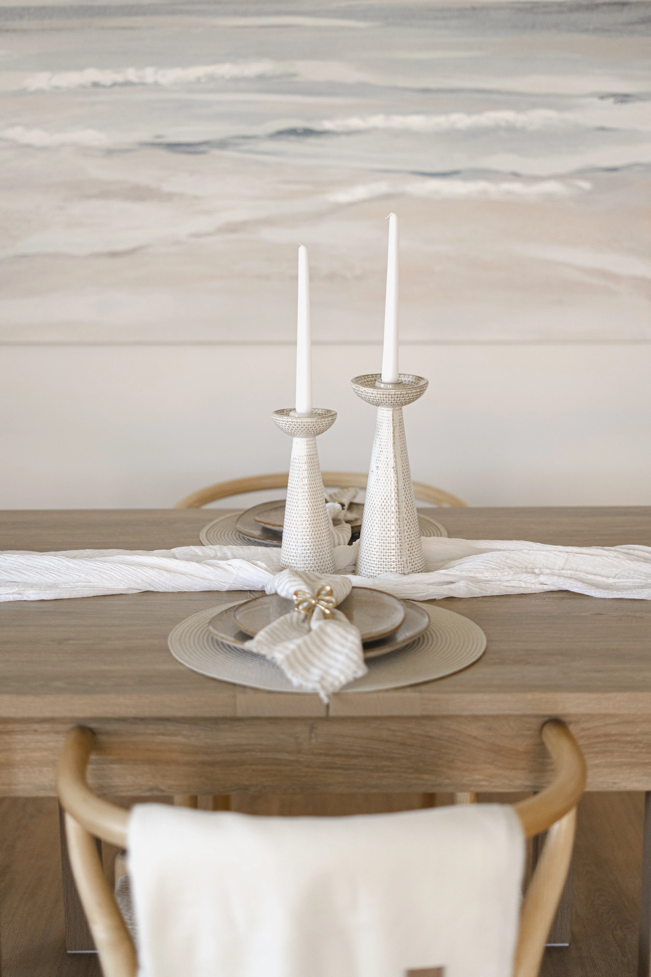 Staged dining area with oak table, neutral table styling, cream accent chairs and large abstract artwork in a contemporary Somerset home.