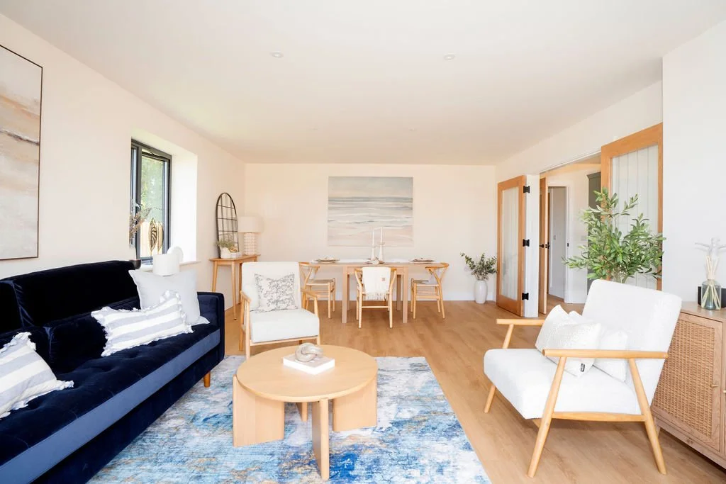 Modern sitting dining room in anew build bungalow. Blue velvet sofa with light wood dining table & console table.