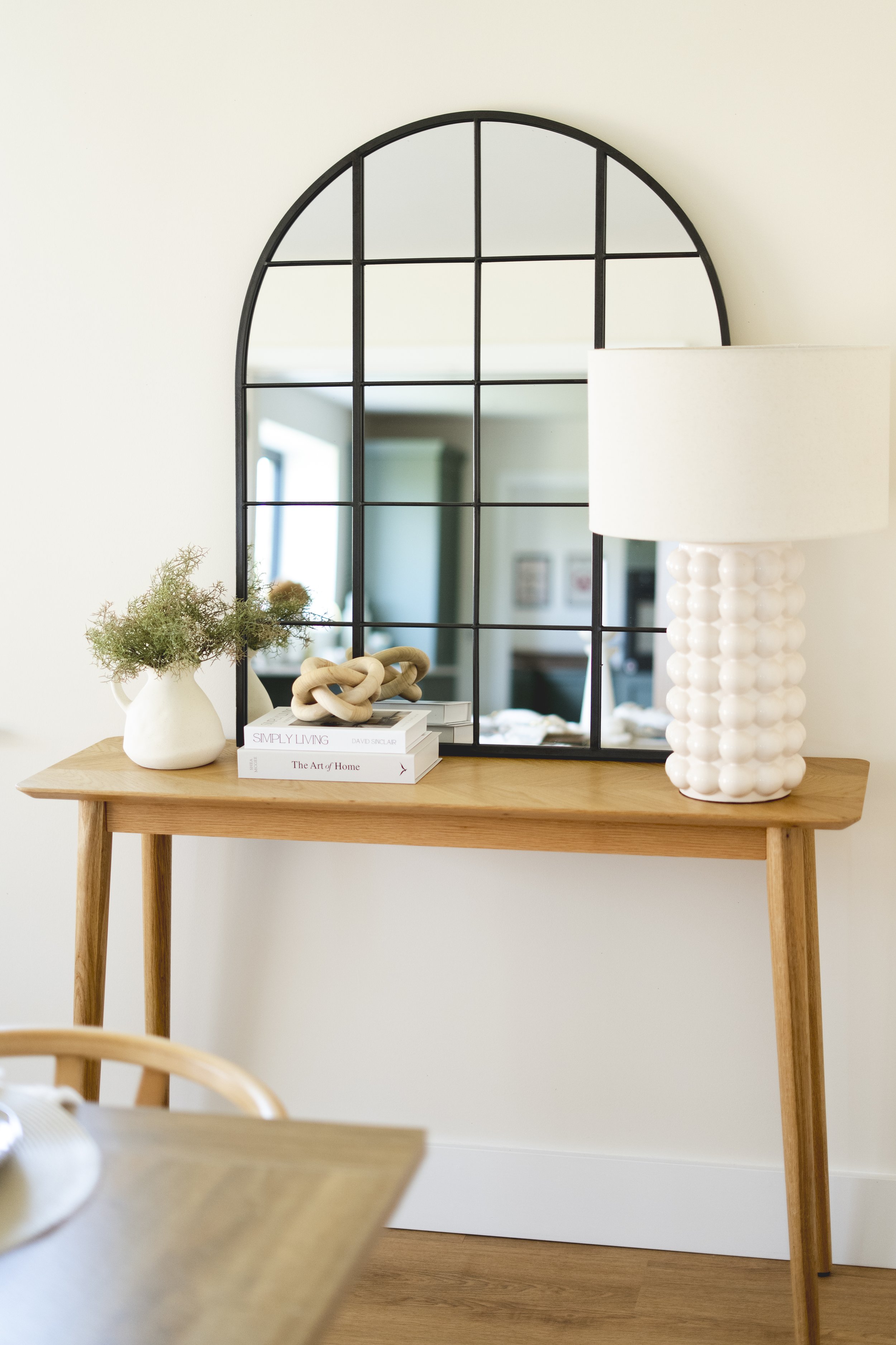 Styled oak console table with arched black mirror, statement lamp and neutral accessories in a professionally staged Somerset home.