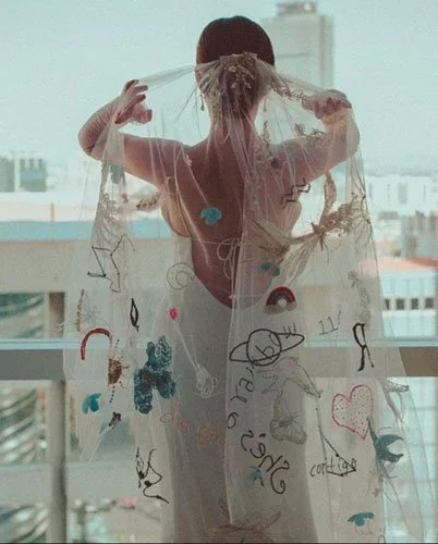 Back view of bride wearing personalized embroidered veil with children’s sketches, a whimsical and creative trend in 2026 wedding veils.