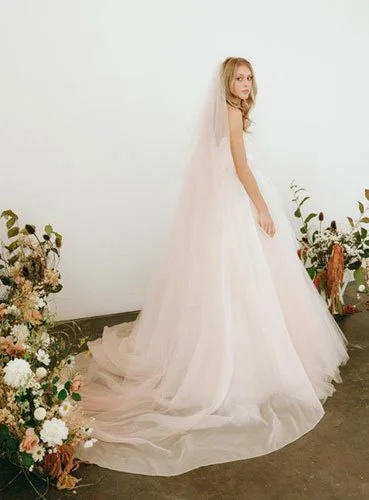 Bride wearing soft pink ombre cathedral veil, a blush-toned statement trending in bridal veil styles 2026.
