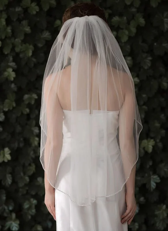 Soft tulle fingertip length wedding veil with beaded and sequin edge, single tier design complementing fitted gown.