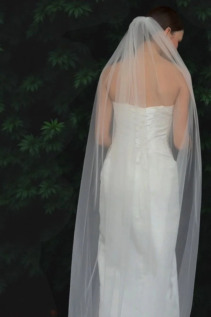 Back view of bride wearing long plain chapel length one-tier tulle veil, clean and elegant modern bridal style.