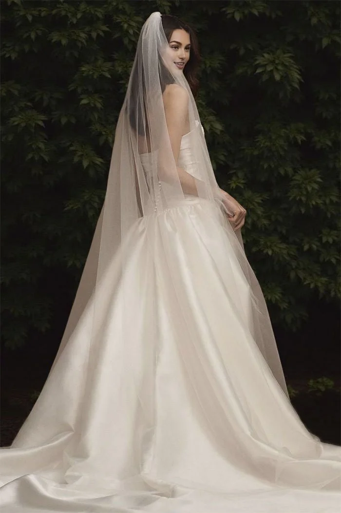 Simple chapel length single layer wedding veil on modern bride, lightweight soft Swiss tulle veil flowing over satin gown.
