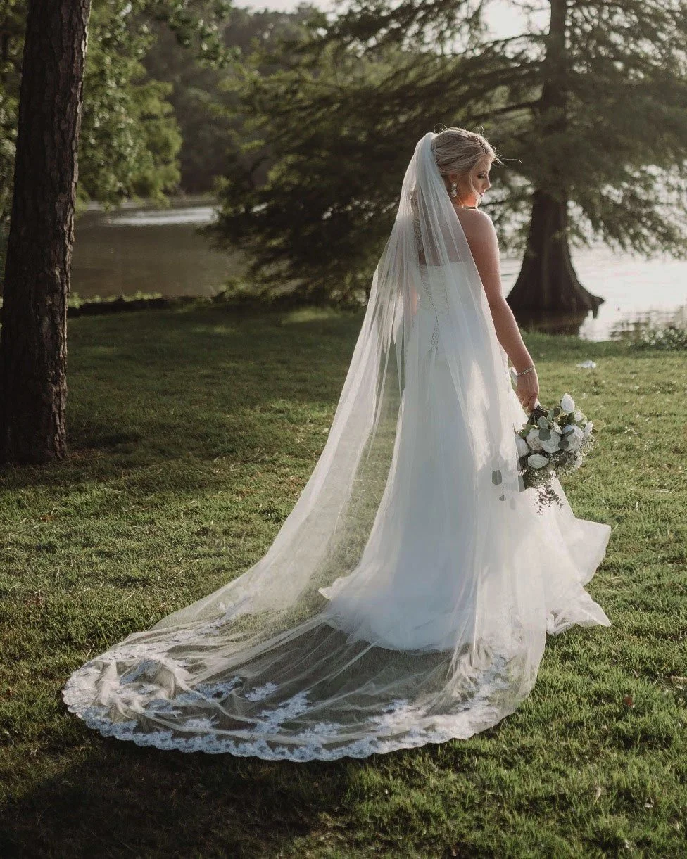 Cathedral wedding veil with floral lace edge in off-white, single tier design flowing elegantly behind bride.