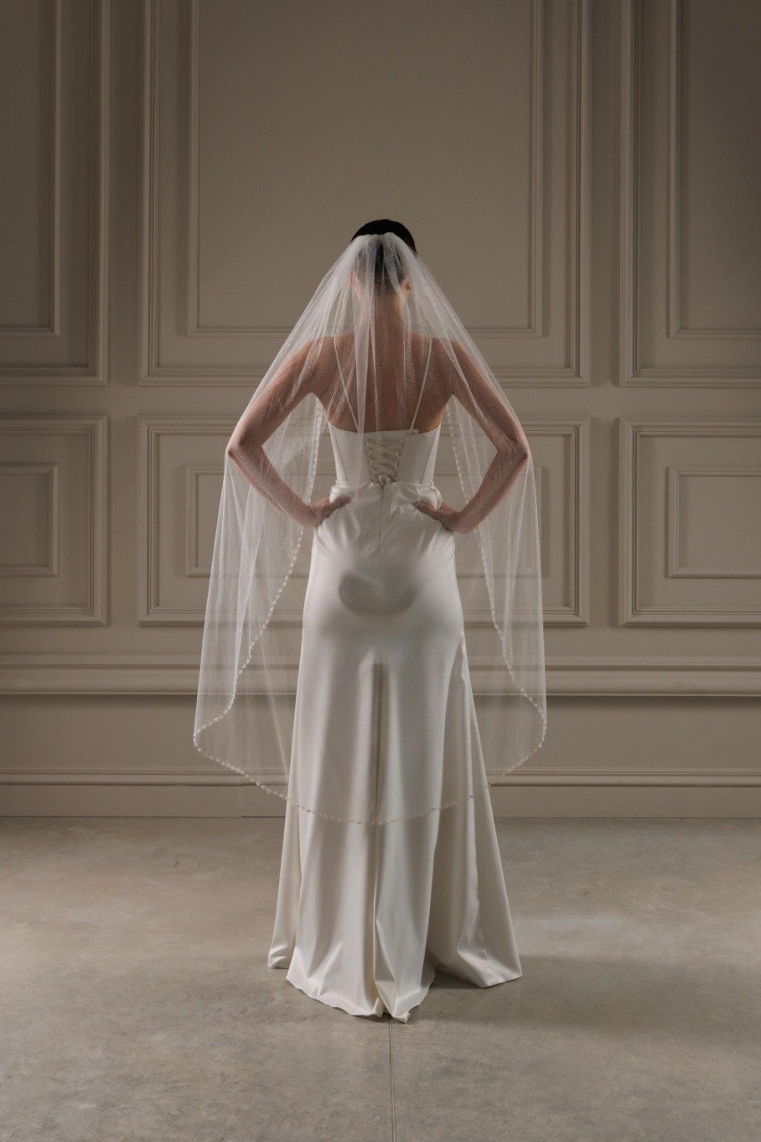 Back view of bride wearing knee length sparkly tulle veil with pearl beaded trim