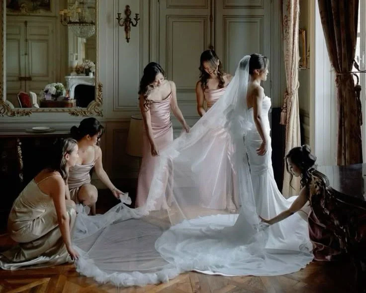 Bridesmaids arranging the bride's ruffle edge cathedral length white wedding veil with long train.