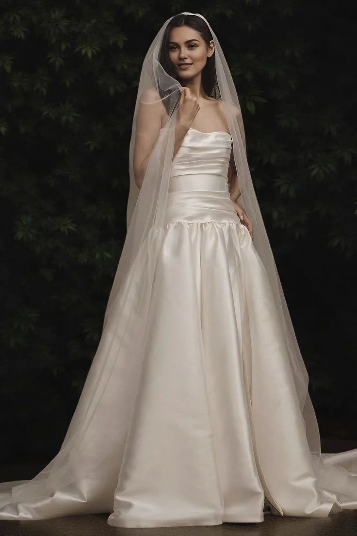 Bride in elegant plain one-tier chapel veil paired with strapless wedding gown, minimalist modern bridal fashion.
