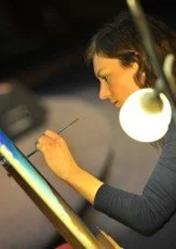 A woman working on a digital drawing at a desk illuminated by a lamp.