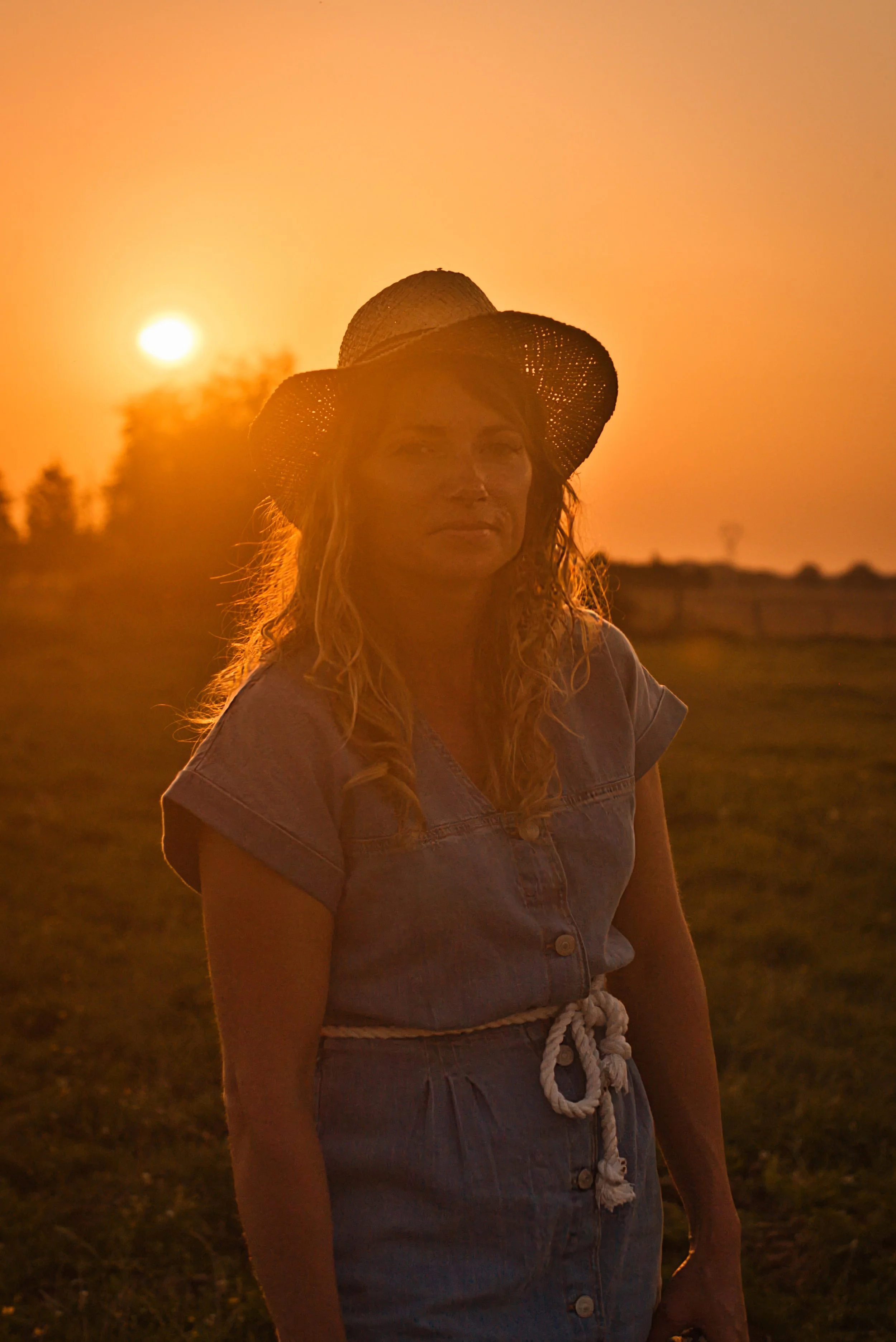 portrait d'une femme avec un chapeau de paille au coucher du soleil