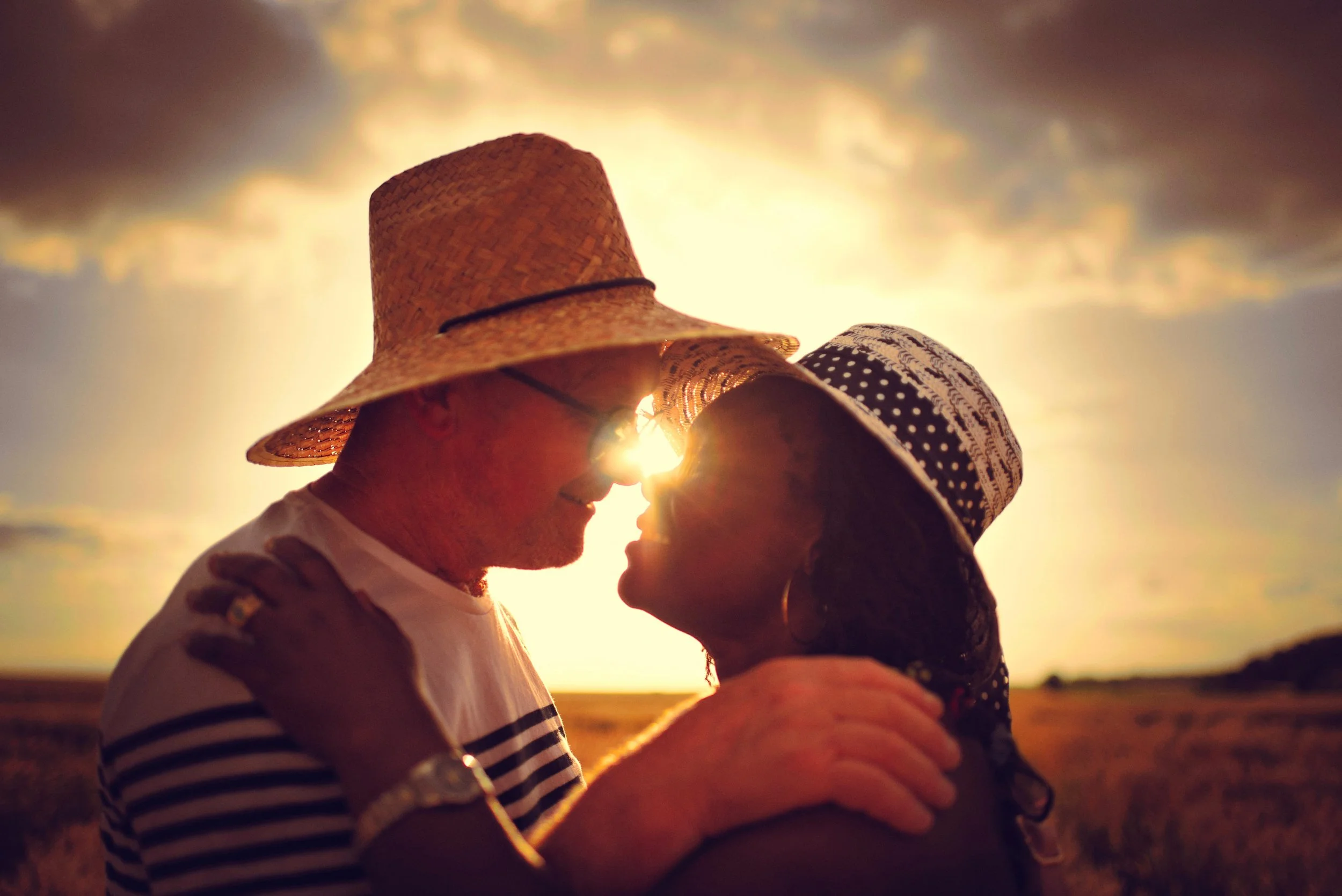 portrait d'un couple qui s'embrasse dans un champ de blé au coucher du soleil