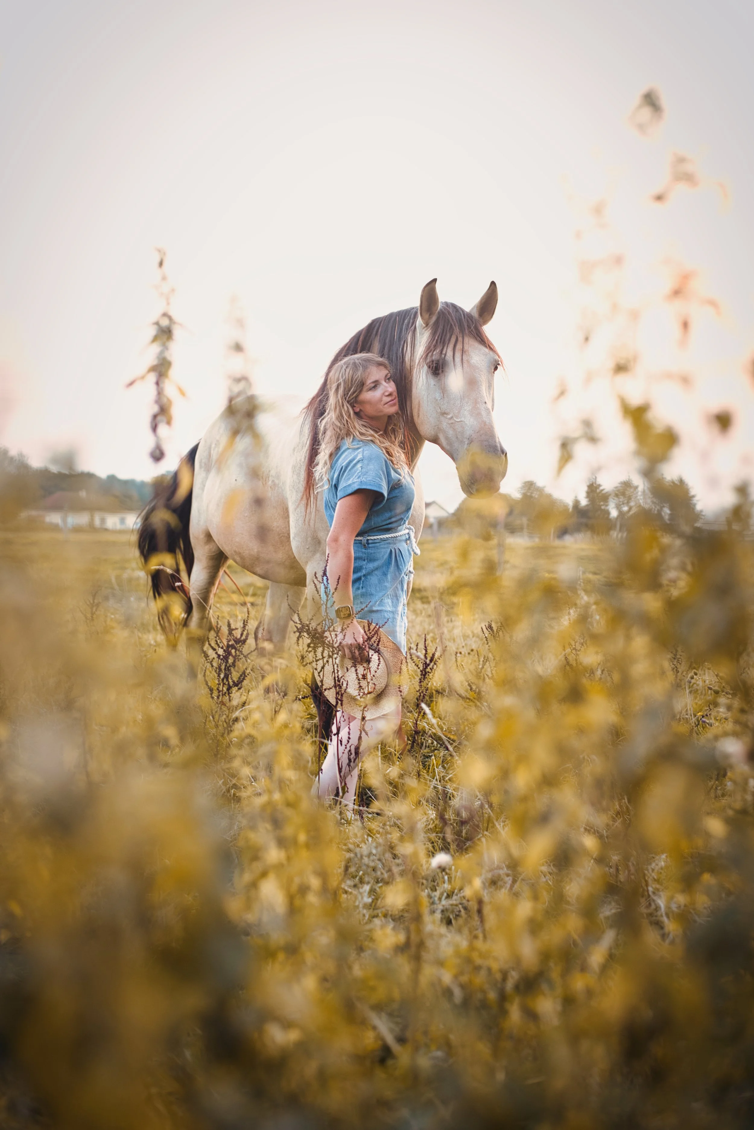 portrait d'une femme avec son cheval dans le parc avec des fleurs jaune