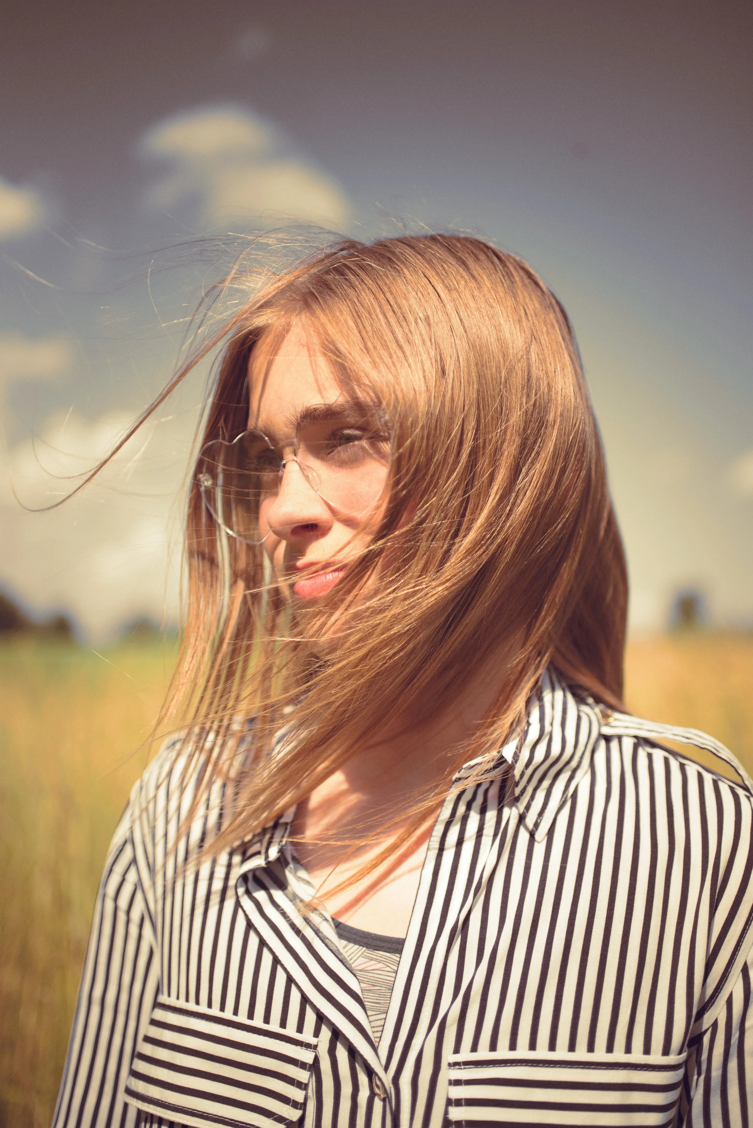 Portrait d'une enfant avec des lunette en forme de coeur transparent, dans un champ de blé
