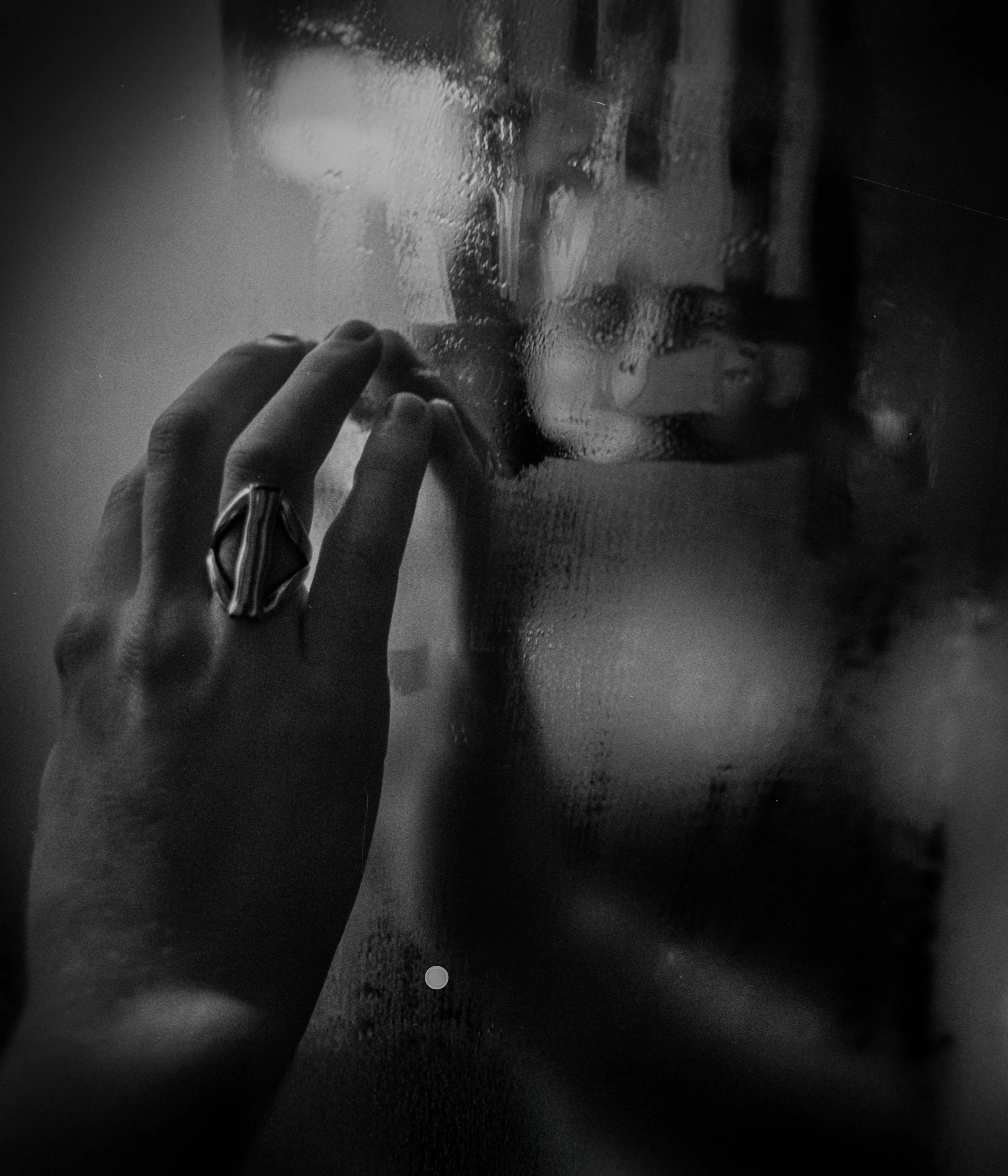 Eine Person berührt eine gläserne, beschlagene Scheibe, hinter der ein kindliches Gesicht sichtbar ist, in Schwarz-Weiß