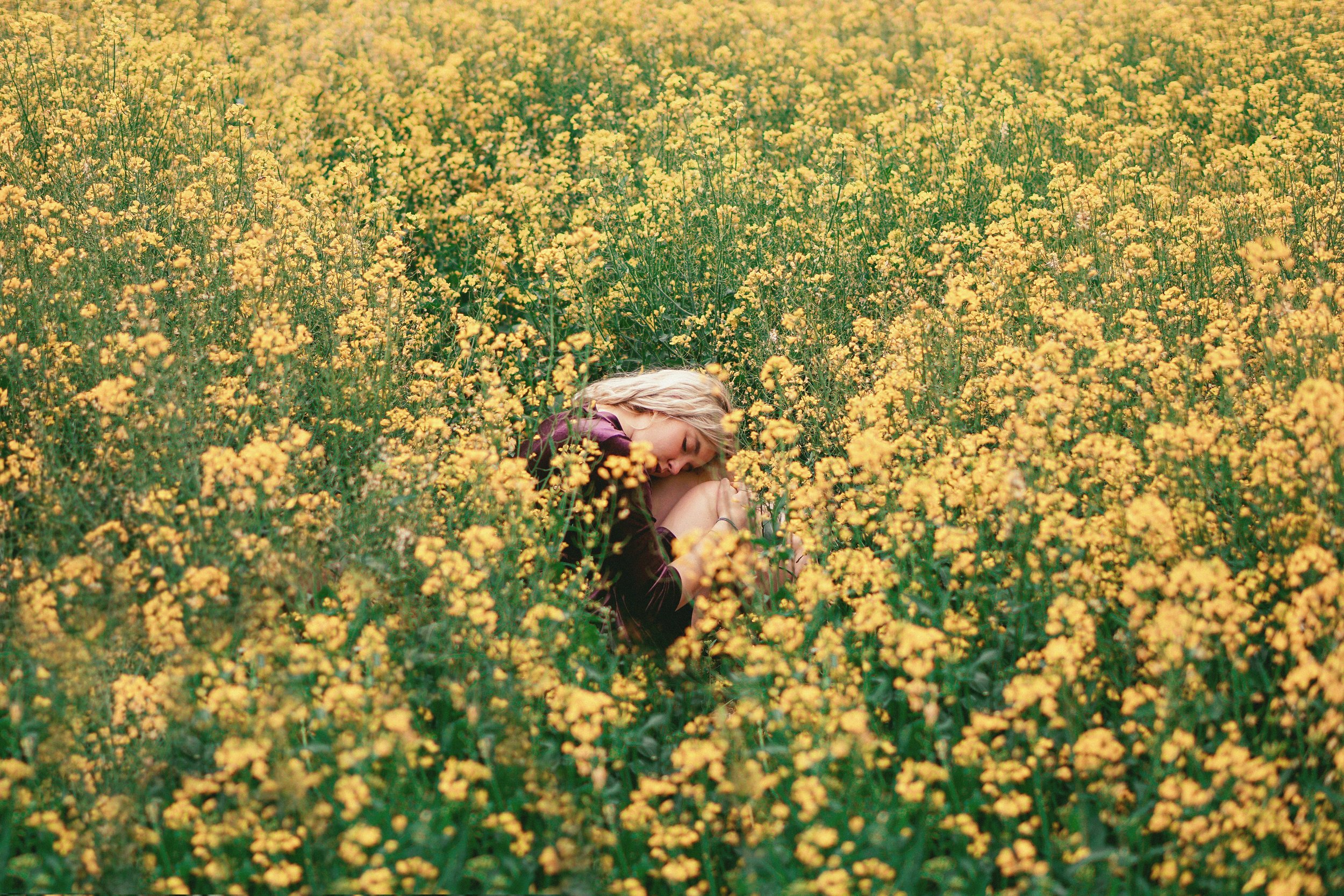 Woman lying in yellow flower field