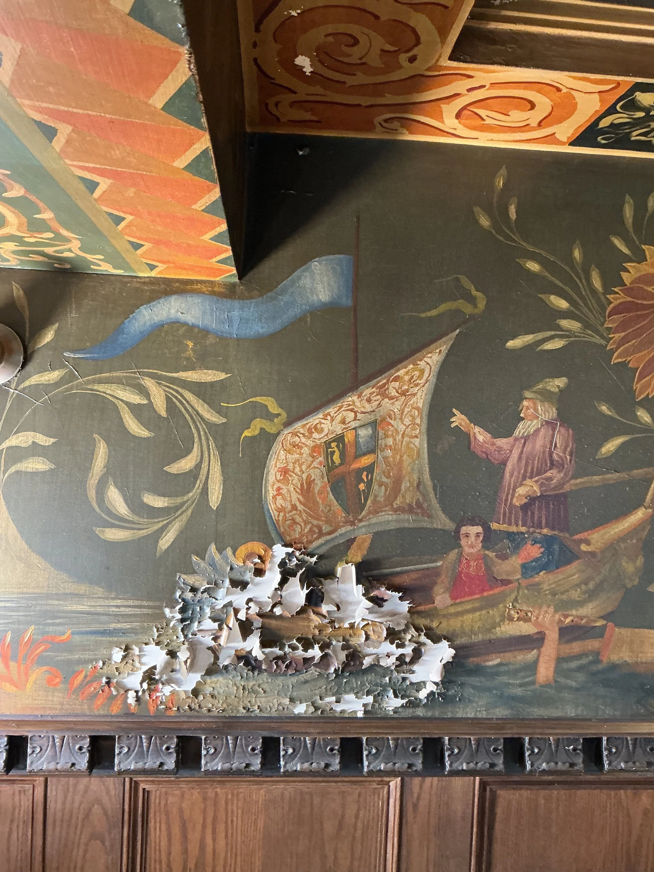 A detailed painting or fresco on a dark wall, featuring a coat of arms with a shield and a crowned figure pointing towards it, surrounded by ornate floral and scroll designs, with a blue snake motif and what appears to be a dramatic scene or figures at the bottom.