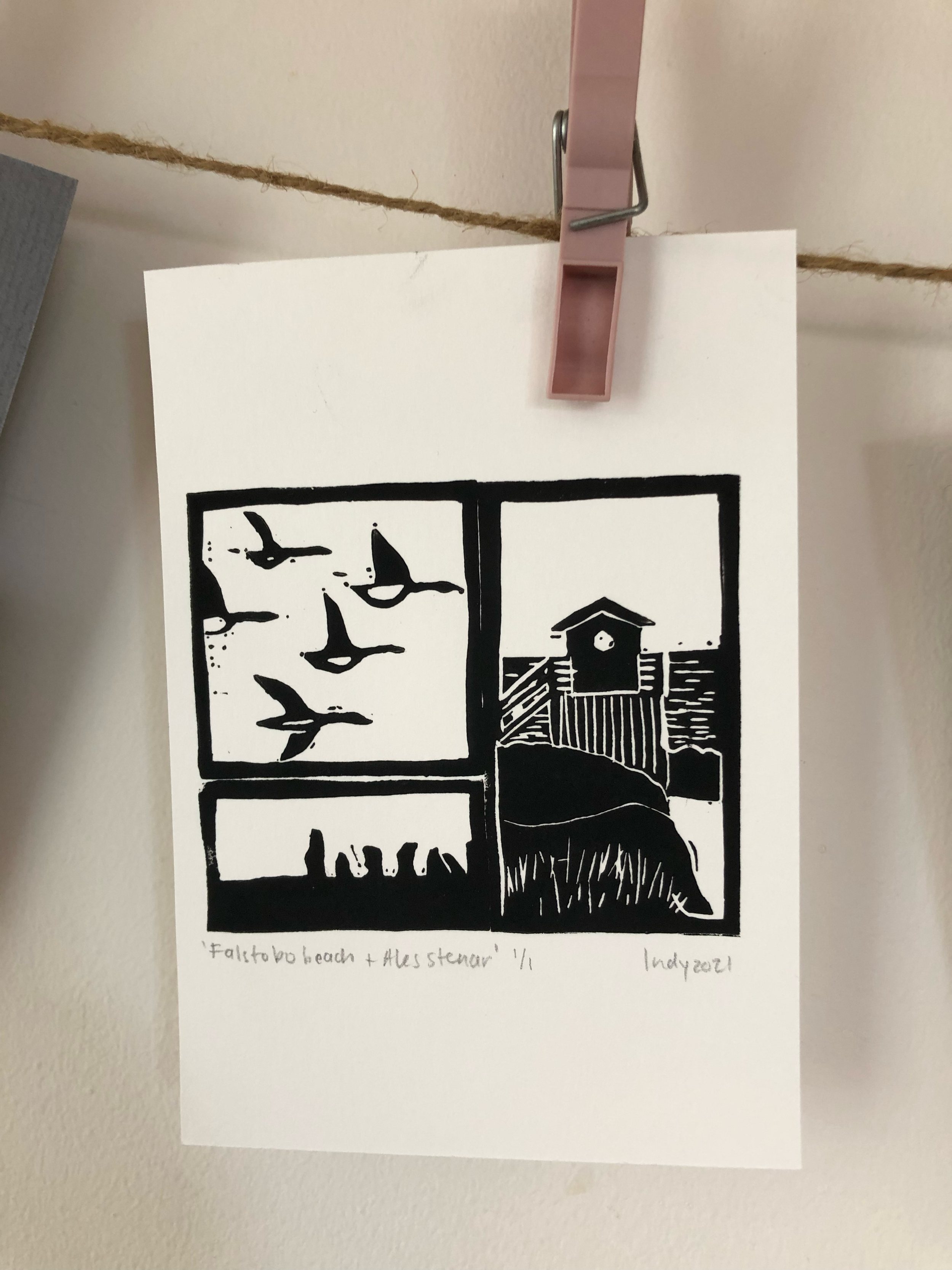Black and white ink drawing of three scenes labeled 'Falkto to beach + Austeran' by Indy 2021, hanging from a clothespin on a string.