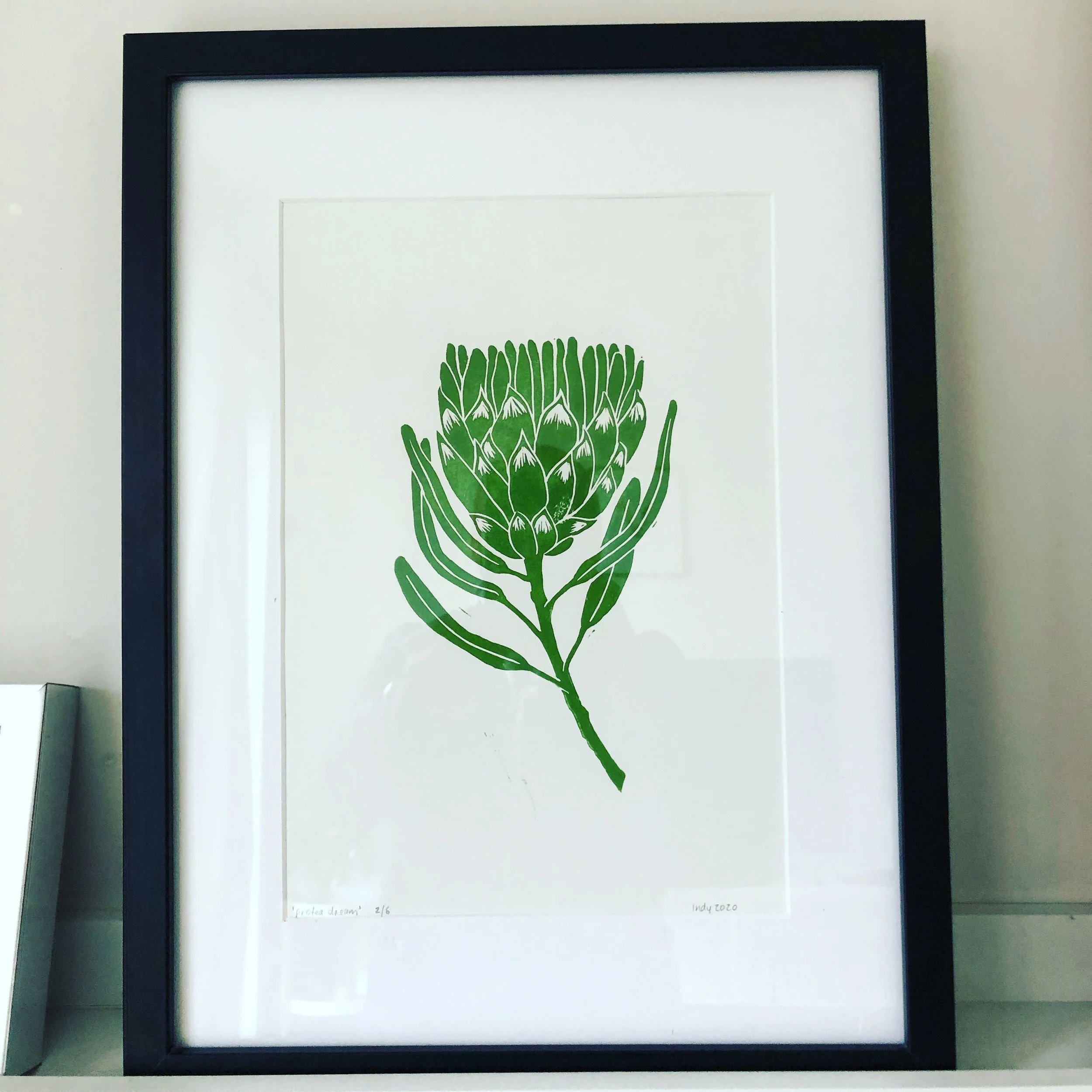 Framed green botanical illustration of a flower on white background.