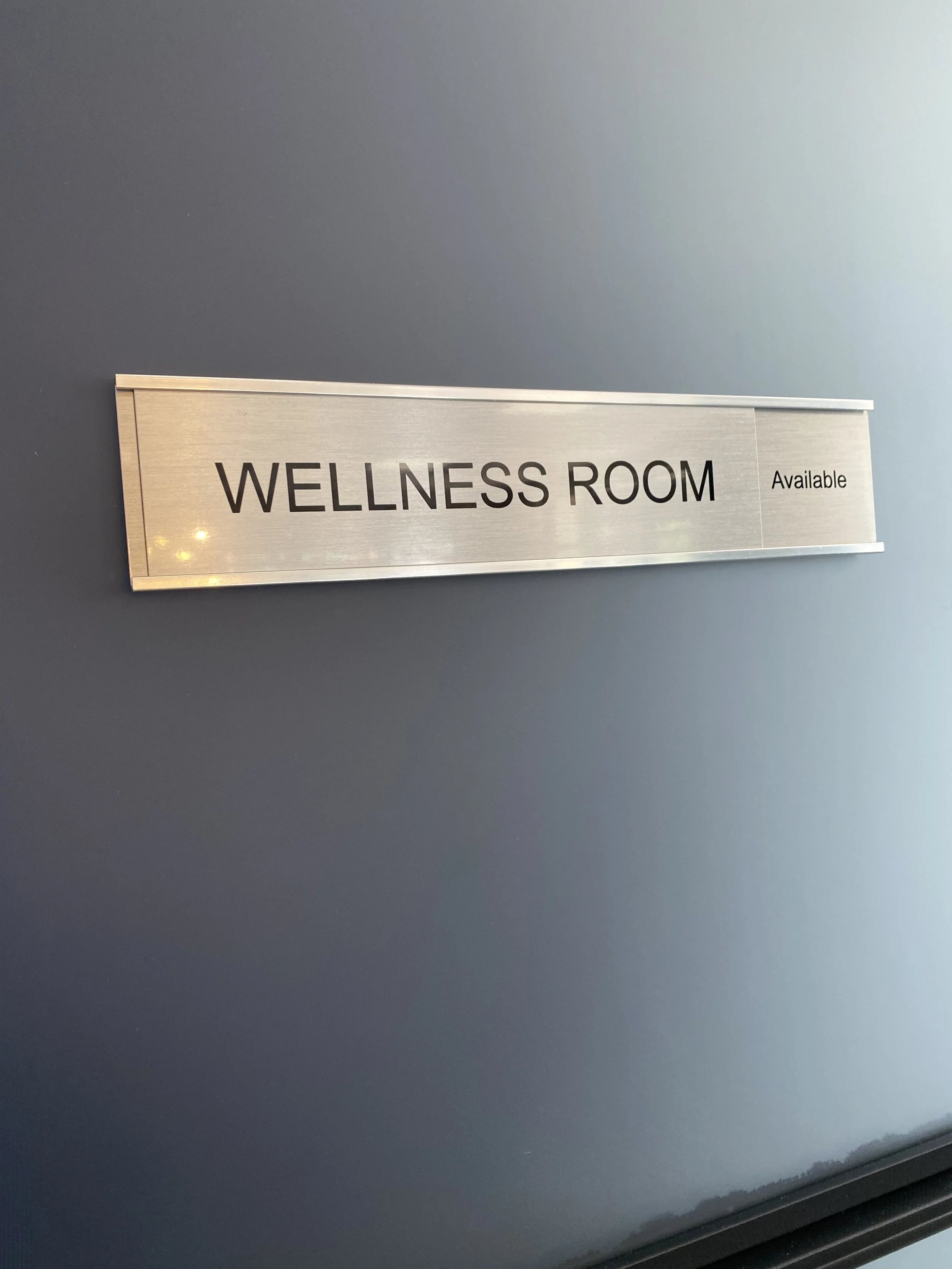 Sign reading "Wellness Room Available" on a wall.