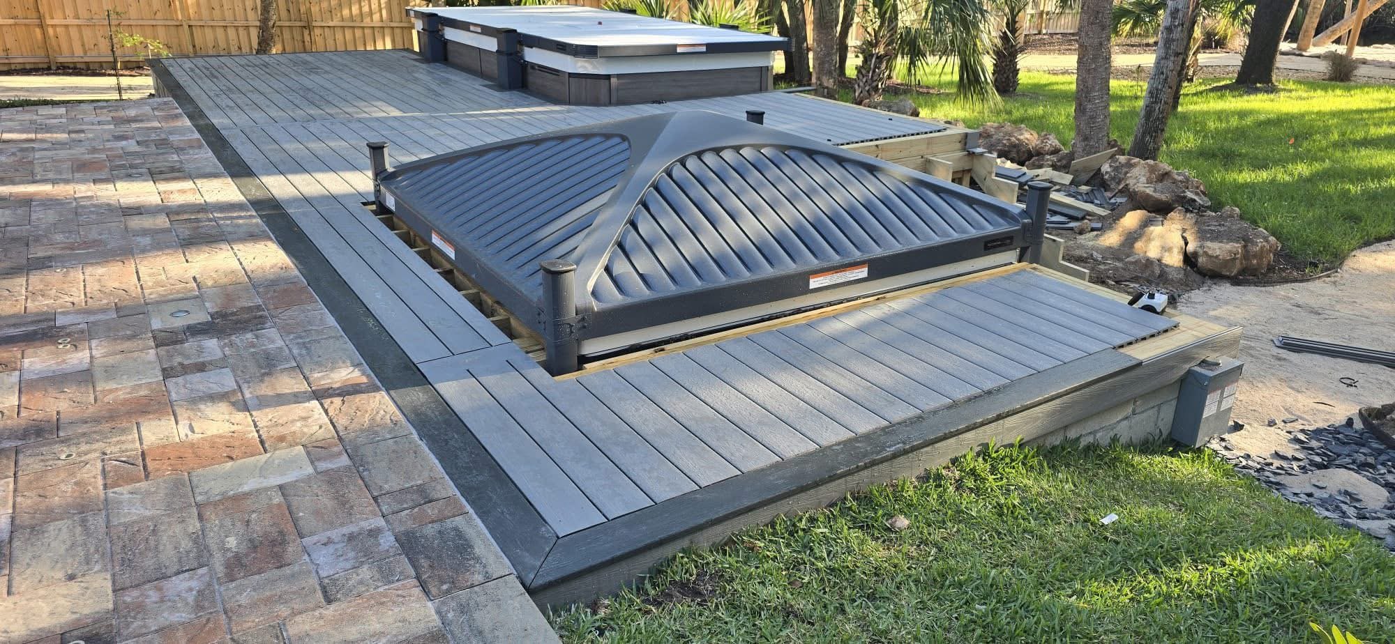 Custom outdoor living and landscape design featuring composite decking, decorative pavers, artificial turf, fire pits, flower beds, and backyard entertainment spaces in Brevard County.