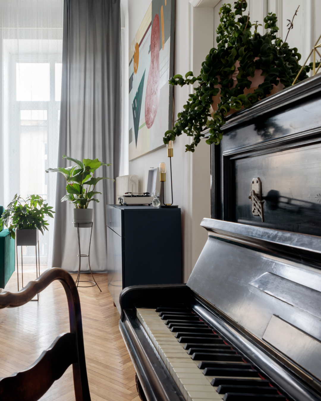 Close-up of a black upright piano with a glossy finish in a living room, showing the keys and a small part of the lid.
