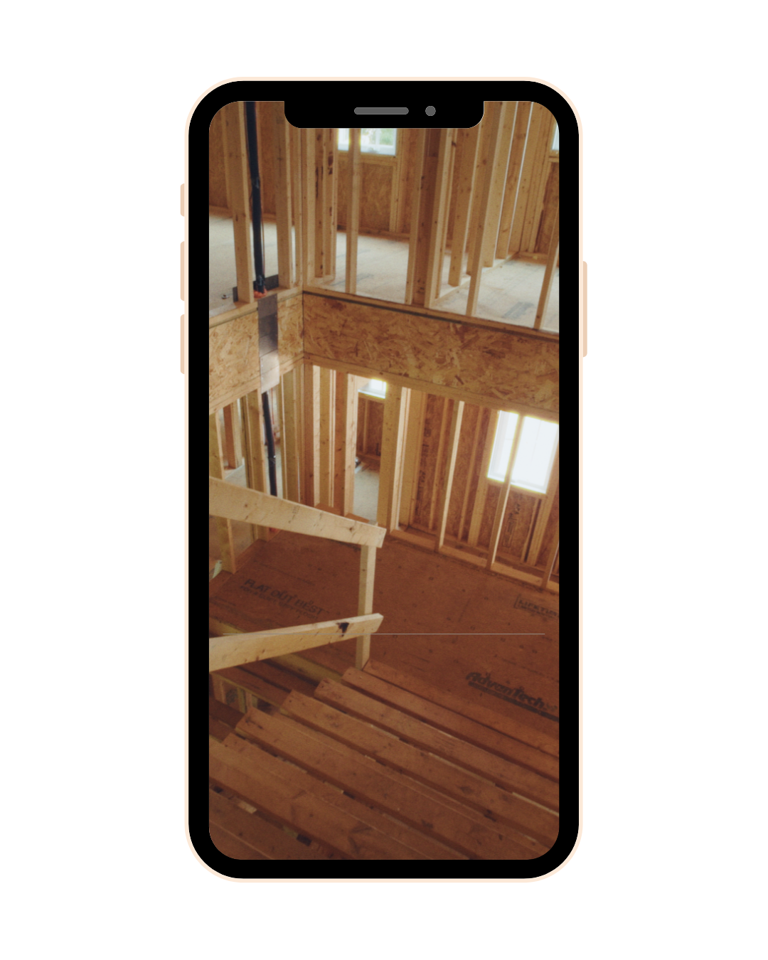 Interior view of a house under construction showing wooden framing and plywood floors, with natural light coming through the windows.
