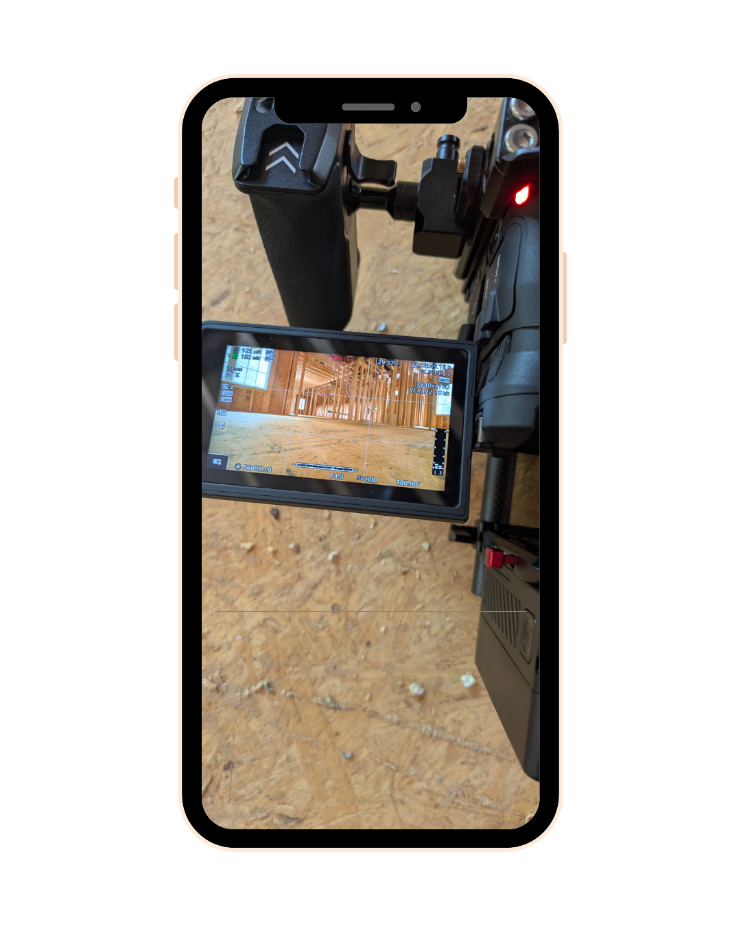 Camera monitor displaying a construction site with wooden framing on a dirt floor.