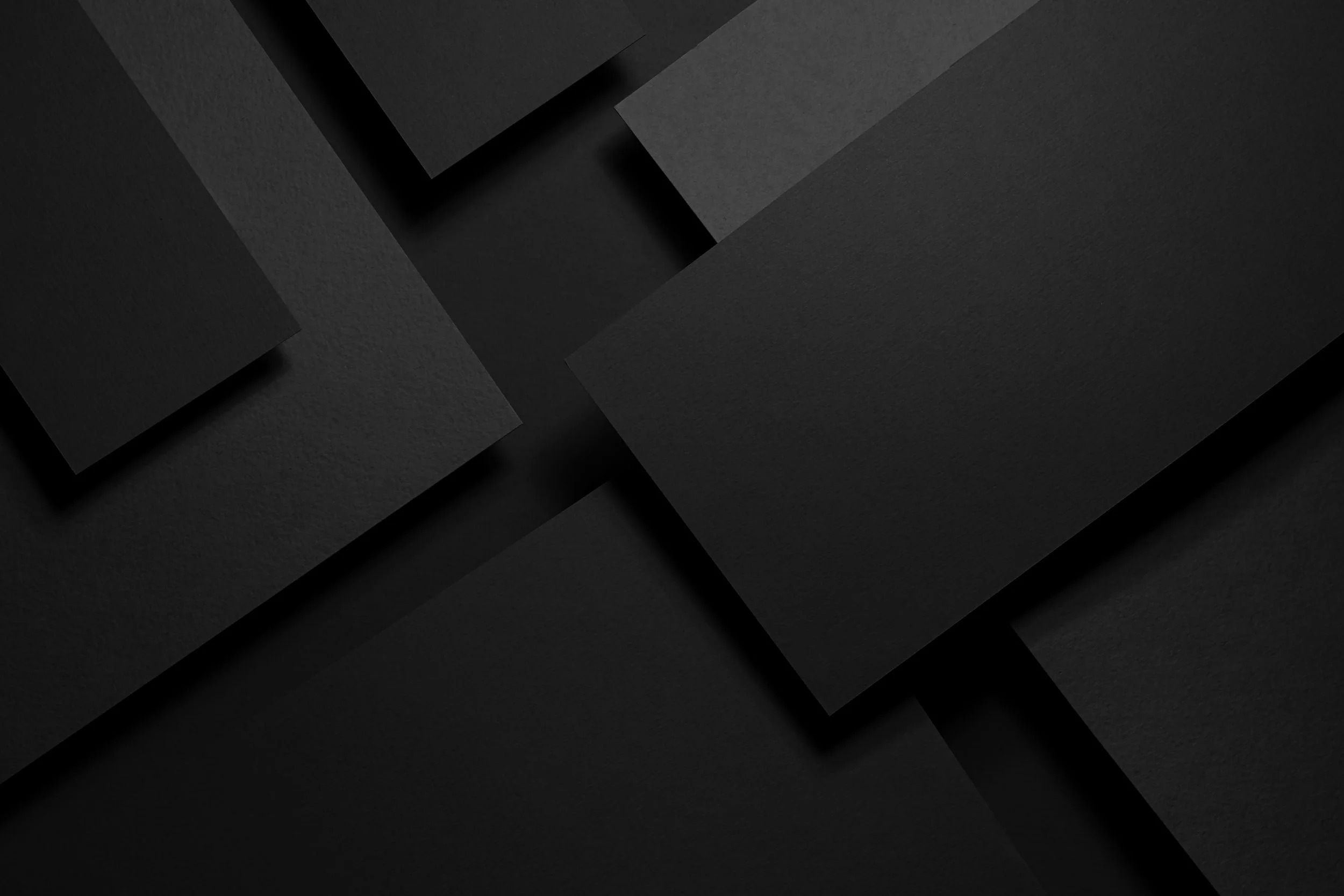 Abstract of overlapping black paper sheets with textured and smooth surfaces.