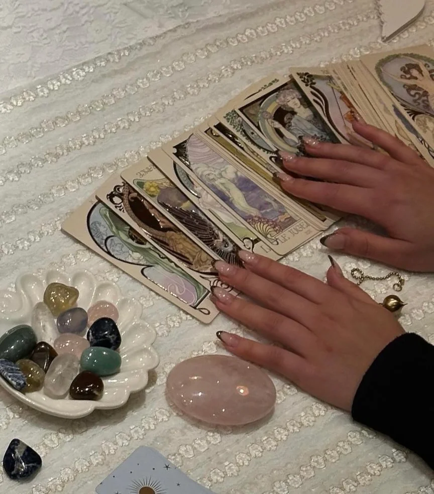 a magical activist's hands rest on a spread of tarot cards