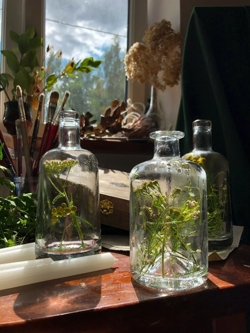 bottled herbs, taper candles and other items used by a witch for spellwork