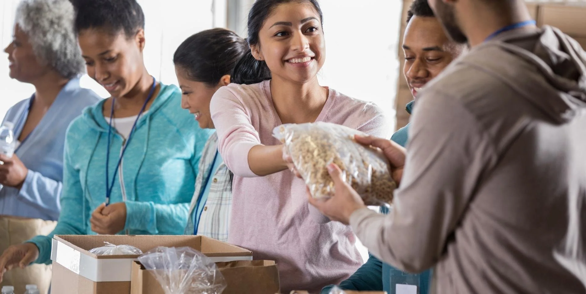 a diverse group of people distributing food from cardboard boxes