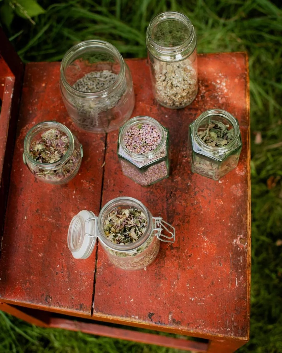 overhead view of various mason jars filled with fresh herbs on a rustic wooden table