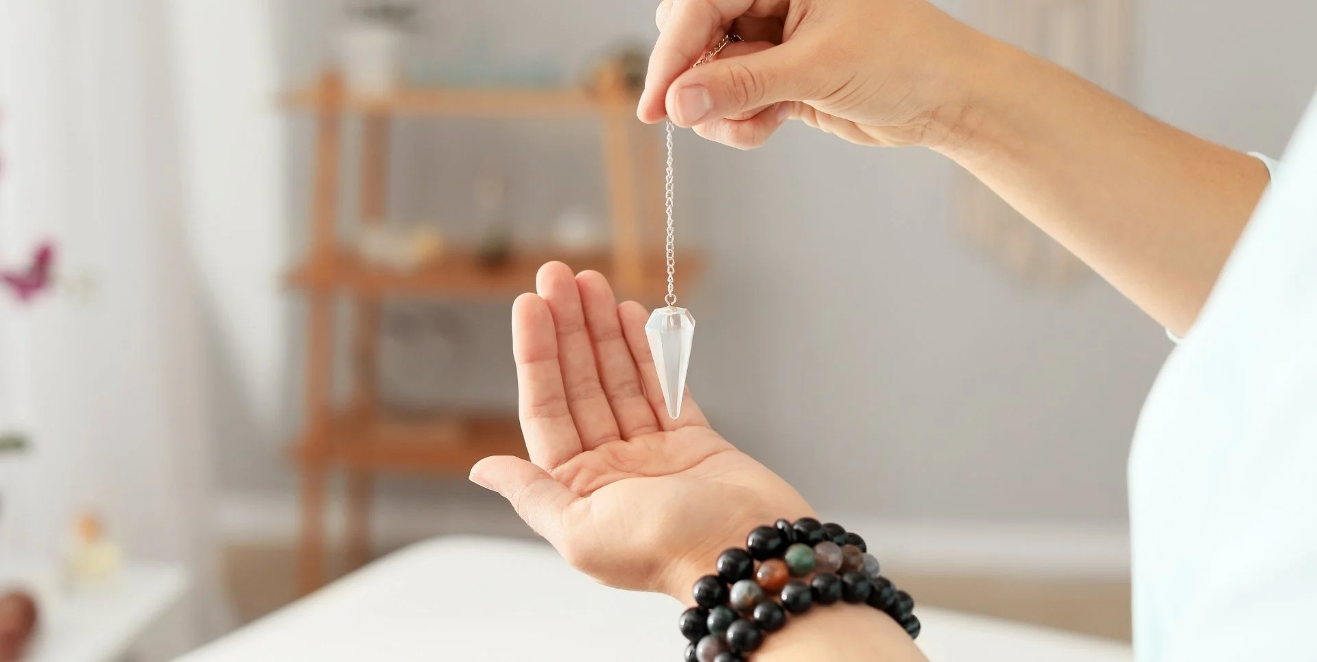 a white woman holding a pendulum in her right hand over her left palm