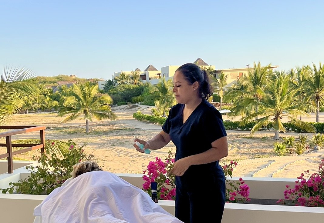 Person lying on massage table receiving a massage, with flowers nearby.