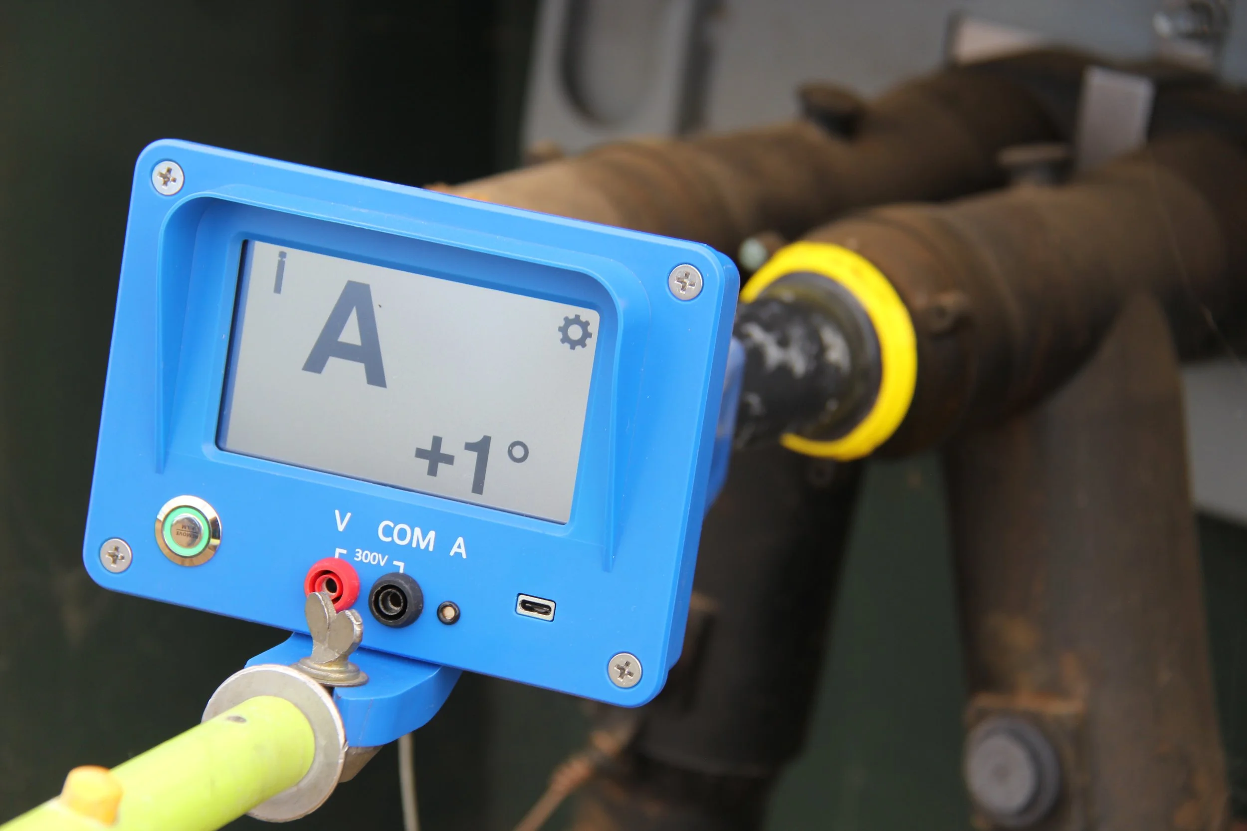 A digital insulation tester displaying a reading of 1 degree Celsius, connected to a cable or pipe wrapped with insulation material.