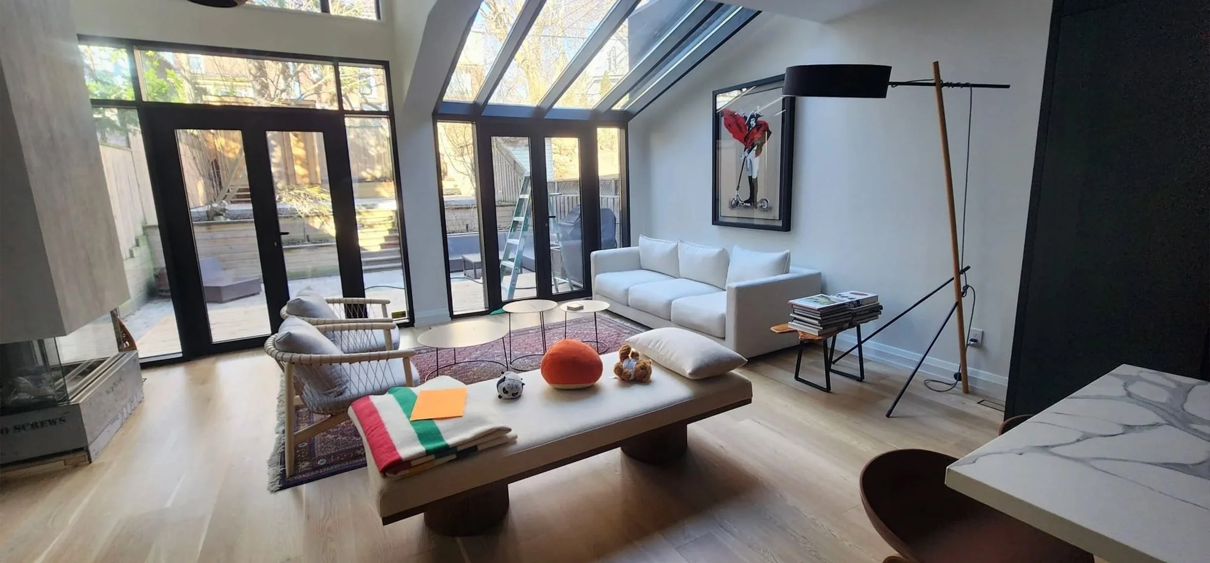 Lantern House living room in The Beaches, Toronto, built by Maxamin Homes, with large windows, white sofa, patterned armchair, and artistic wall decor.