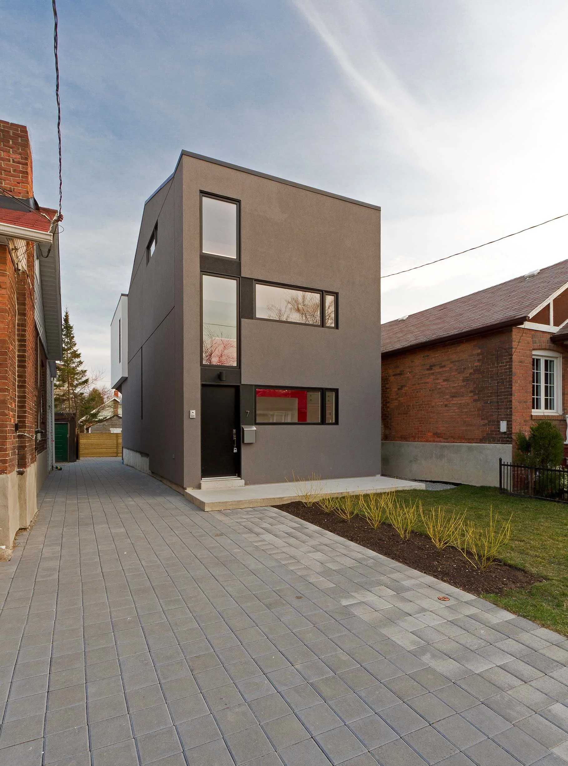 Whale House exterior in East York, Toronto, built by Maxamin Homes, gray three-story design with large windows, black door, and concrete steps.