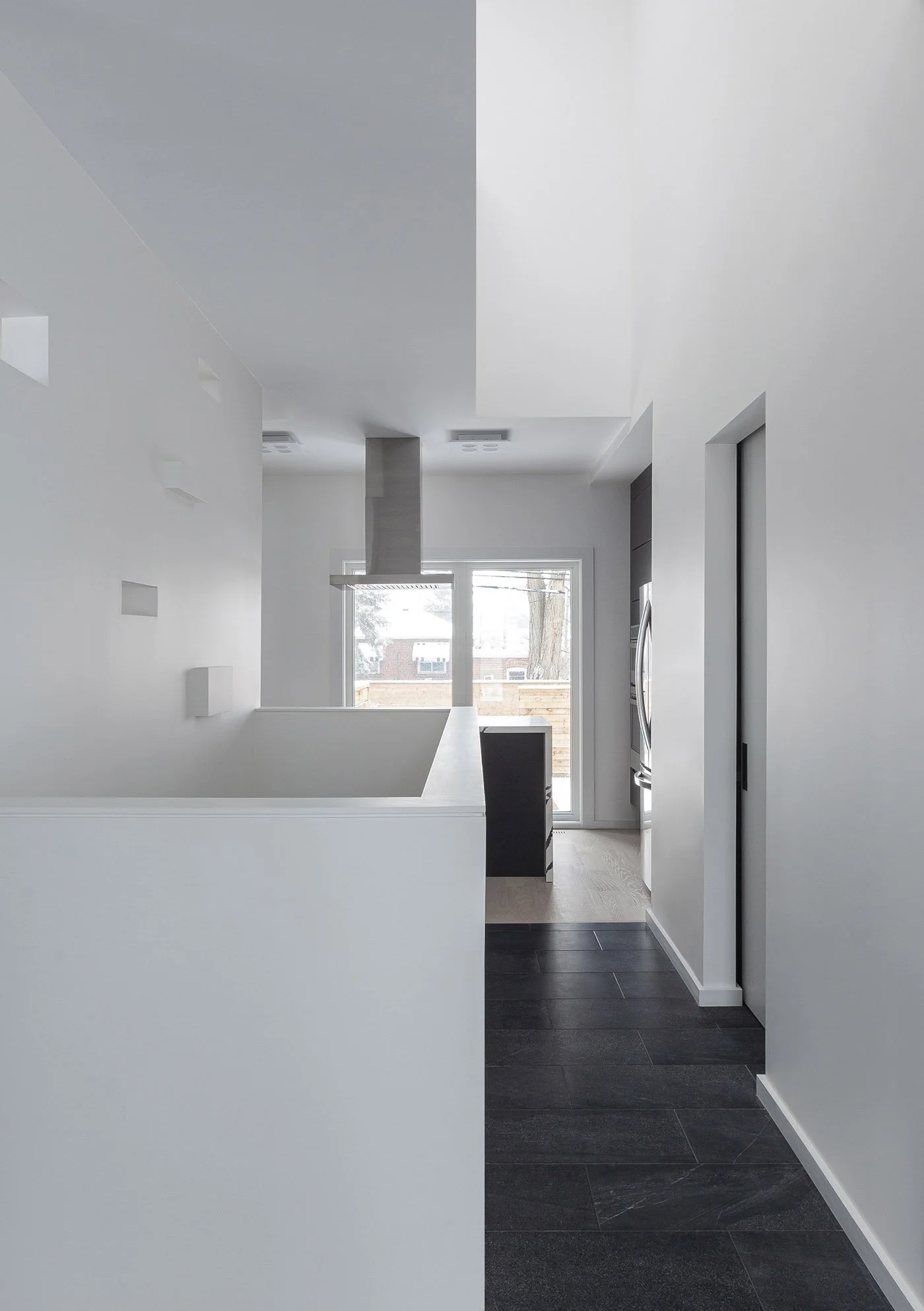 Albers House interior in Scarborough, Toronto, built by Maxamin Homes, minimalist design with sliding glass door, gray walls, and dark flooring.