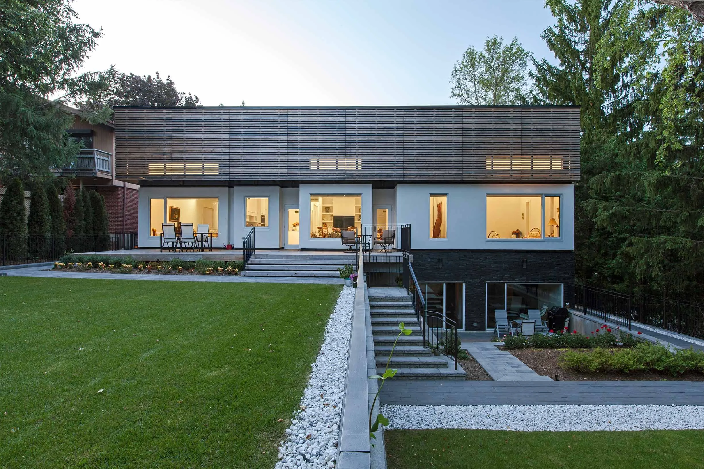 Gallery House exterior in East York, Toronto, built by Maxamin Homes, two-story white home with wooden slats and driveway under evening light.