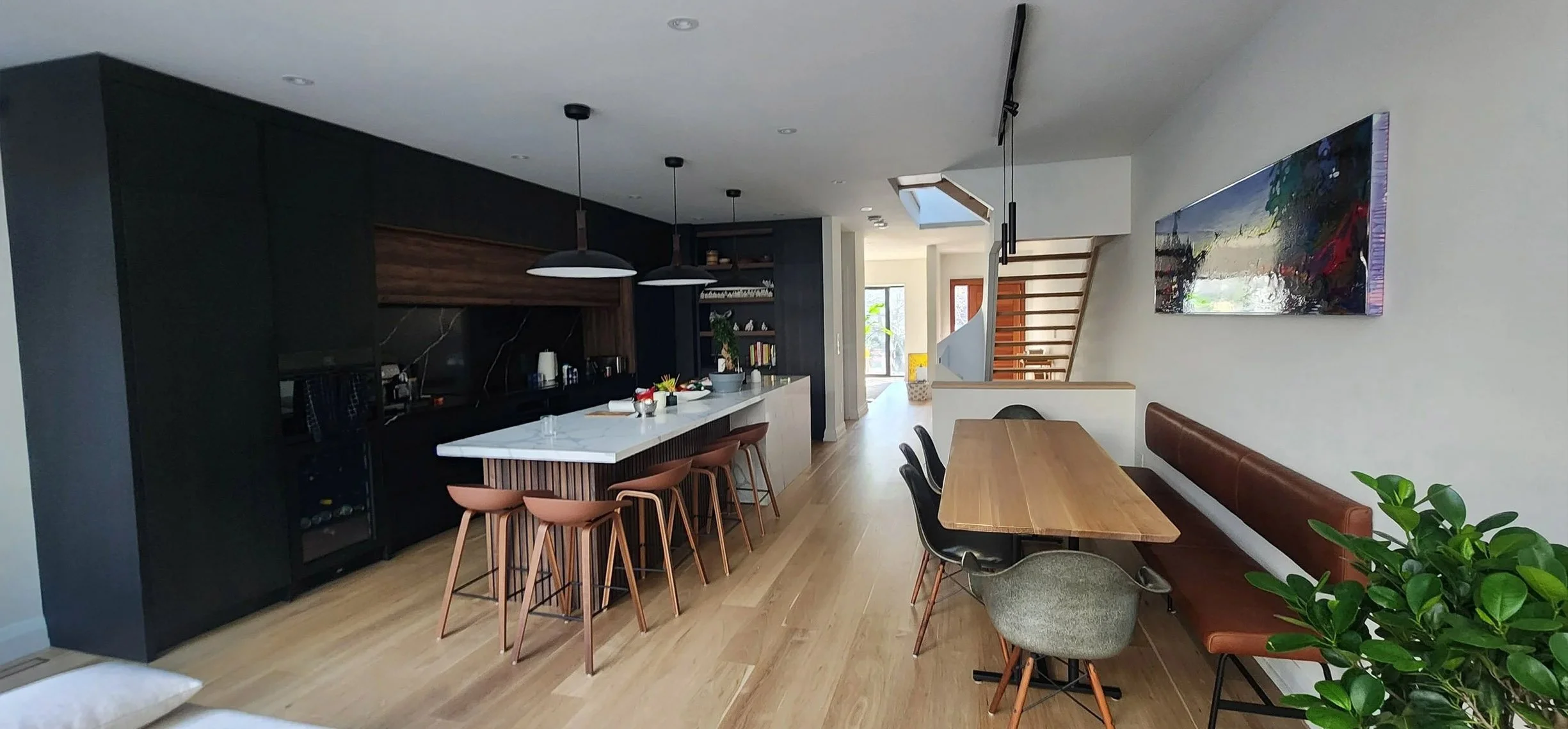Lantern House kitchen and dining area in The Beaches, Toronto, built by Maxamin Homes, with black cabinetry, marble island, and wooden dining table.