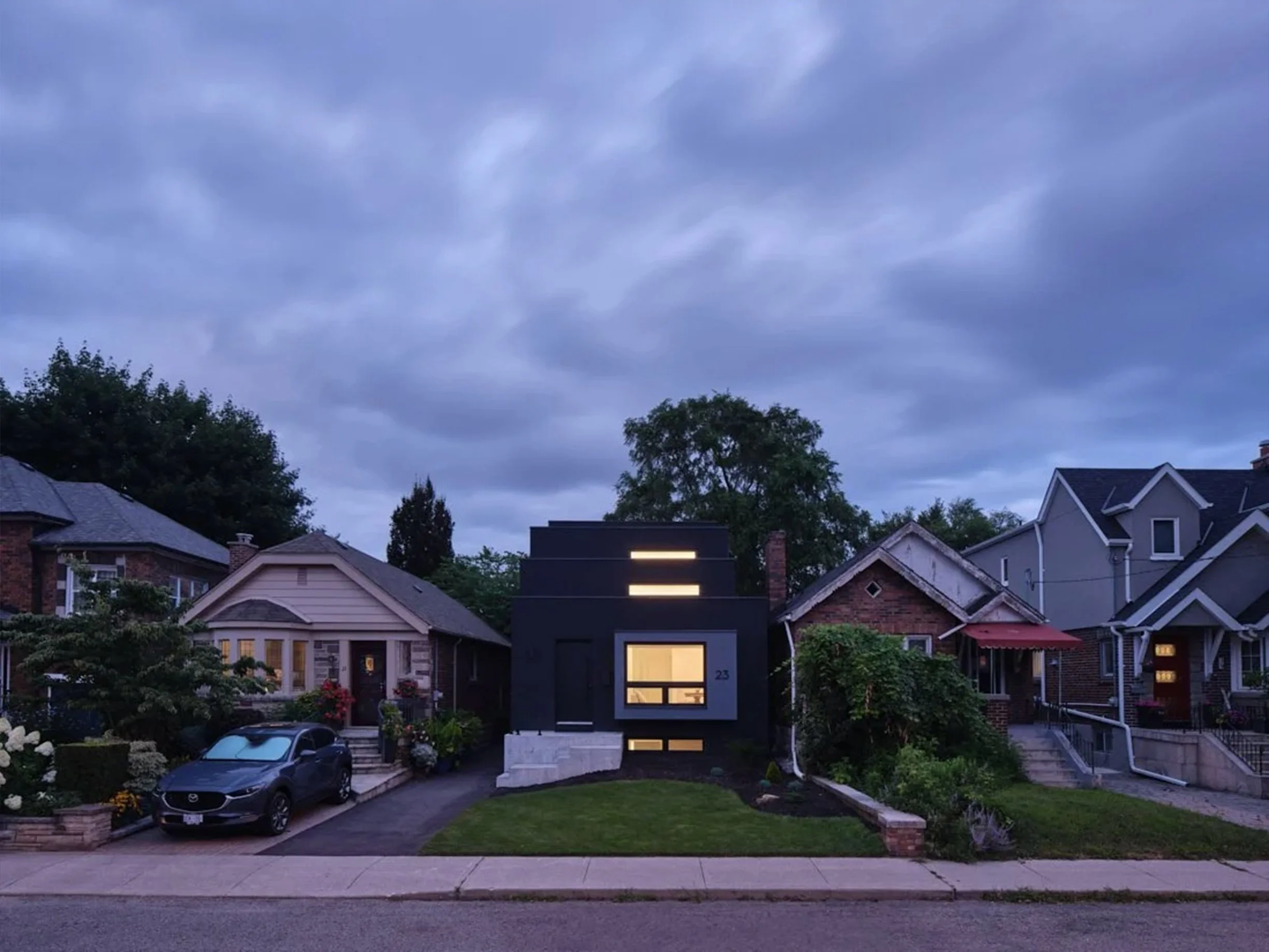Periscope House, a modern black home in East York, Toronto, built by Maxamin Homes, featuring horizontal window slits and large front window.