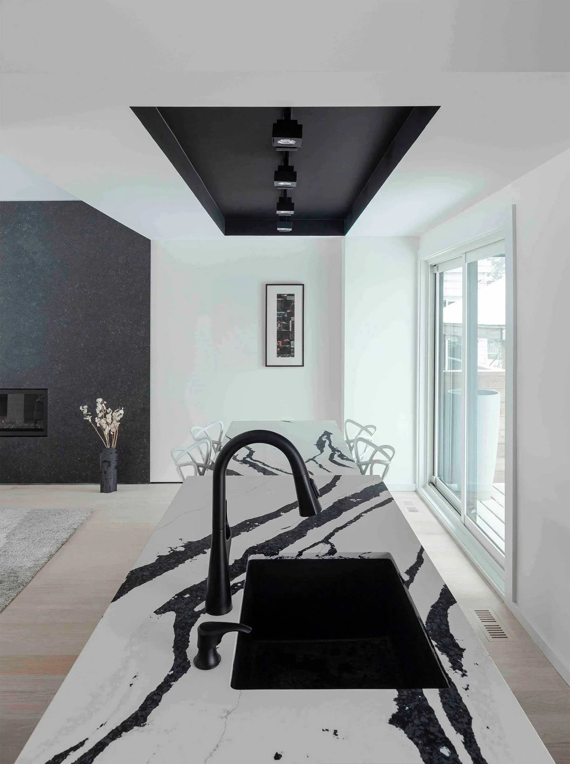Albers House kitchen in Scarborough, Toronto, built by Maxamin Homes, featuring marble countertop, black faucet, white chairs, and wall artwork.